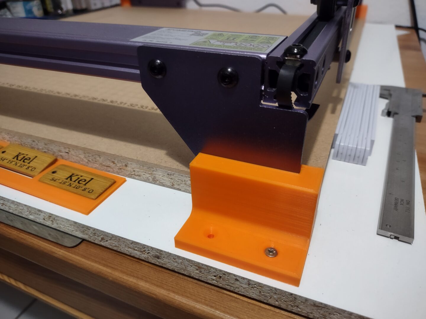 Selbstgedruckte orangene Füße, die auf der Grundplatte montiert sind und den Rahmen des Lasers halten